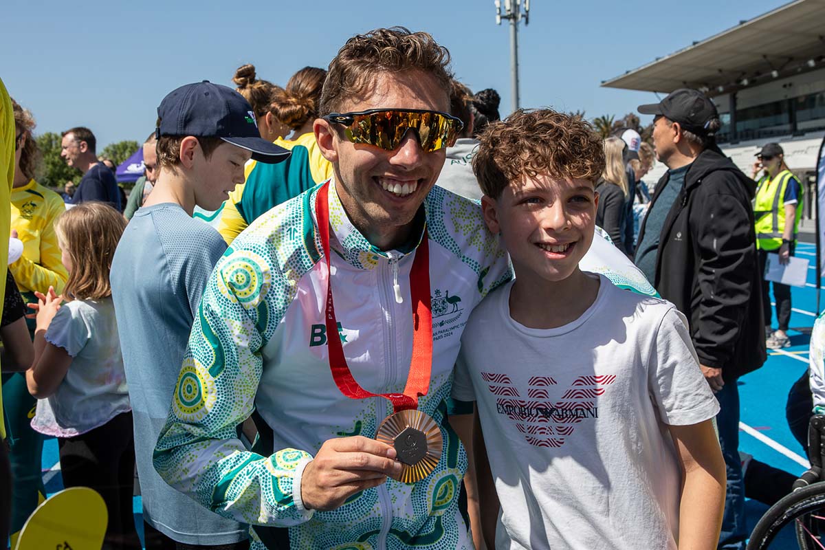 Reece displays his bronze medal while taking a photo with a young fan.