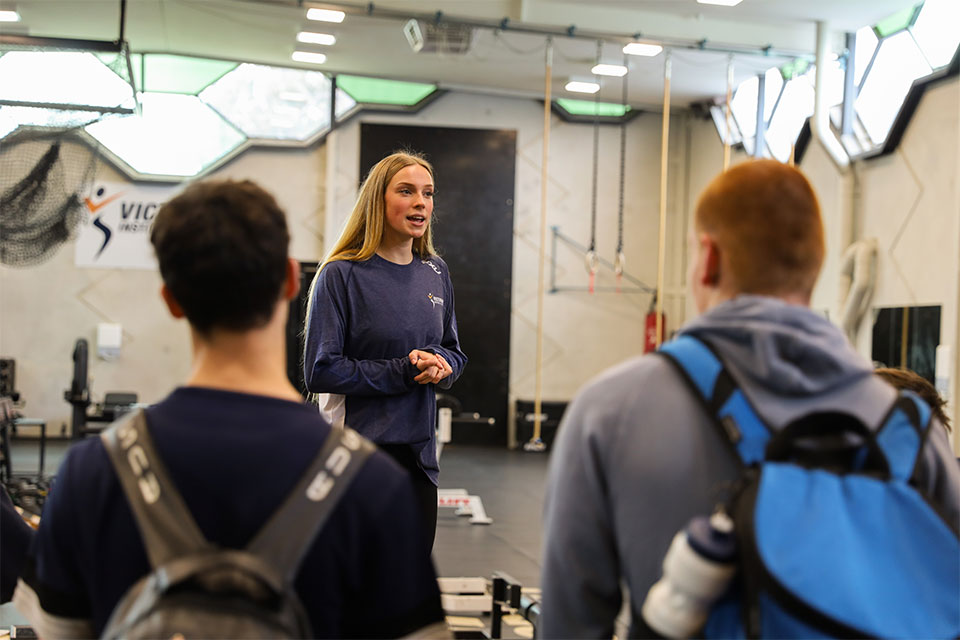Swimmer Tara Kinder shows young athletes through a gym at the Victorian Institute of Sport.