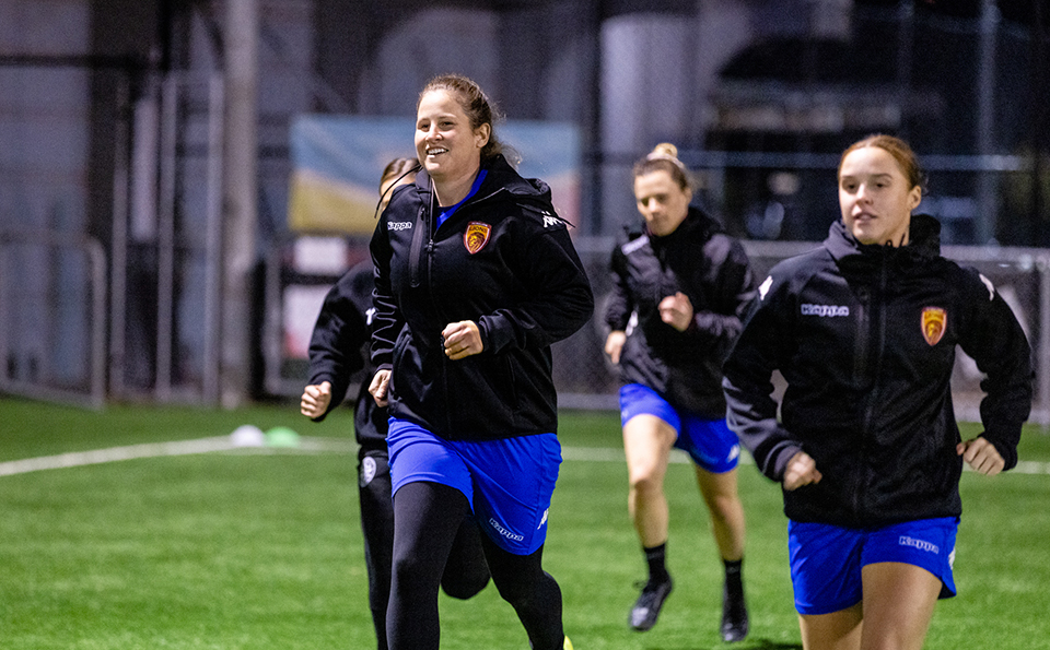 Four women warm up at football training.