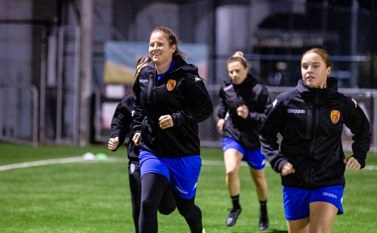 Four women warm up at football training.