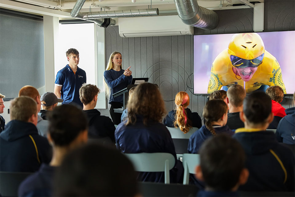 Swimmer Tara Kinder and hockey player Freddy Waters present to a group of young athletes.