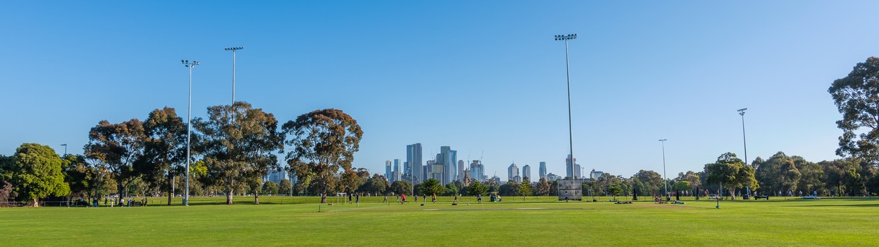 Lighting towers are seen at a sports ground at Princes Park with the skyline of Melbourne in the distance.