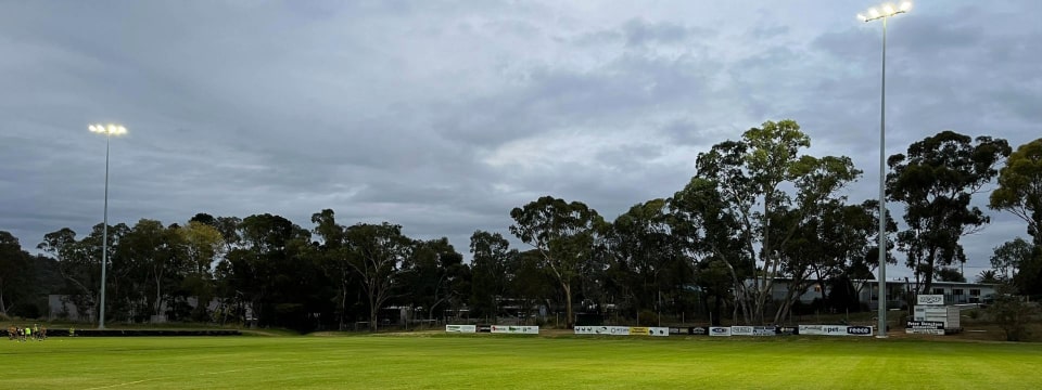 Harcourt Recreation Reserve with the lights on at dusk.