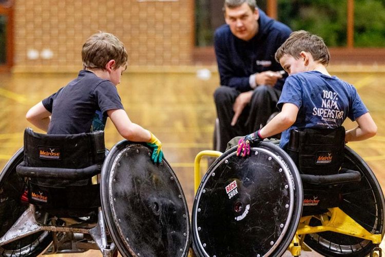 Two boys with disabilty play wheelchair sport.