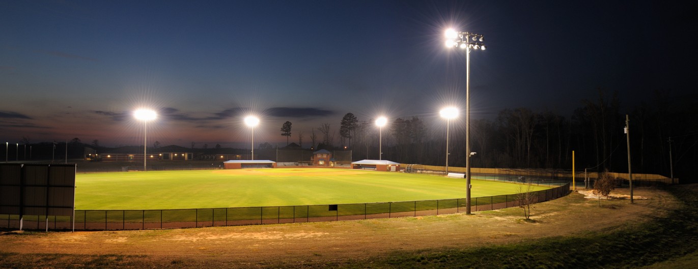 A baseball field at night, lit up by 5 lighting towers.