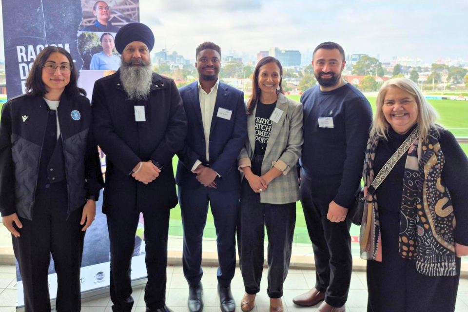 Spokespeople standing in front of anti-racism in sport campaign banner