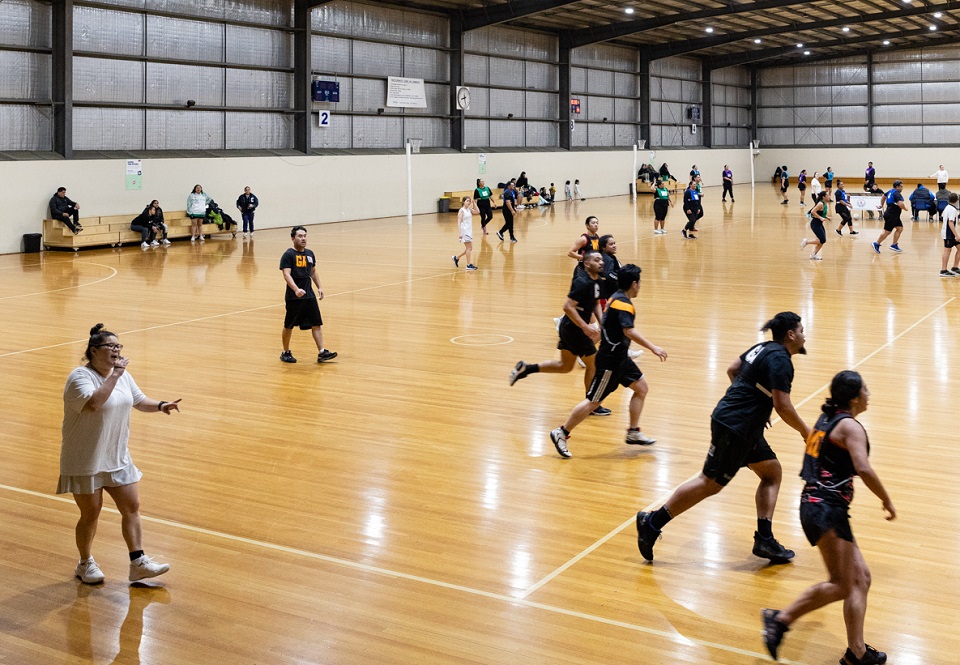 Netball umpire and players on an indoor court