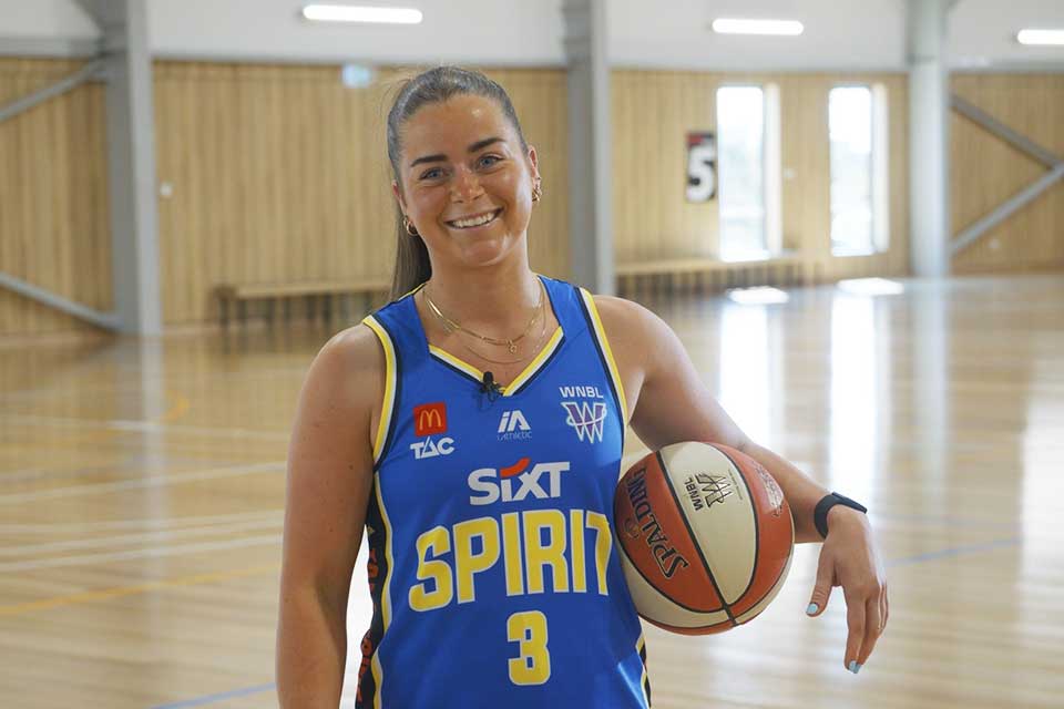 Georgia Booth, guard for the Bendigo Spirit basketball team. Georgia Booth in Spirit team uniform holding a basketball under her arm.
